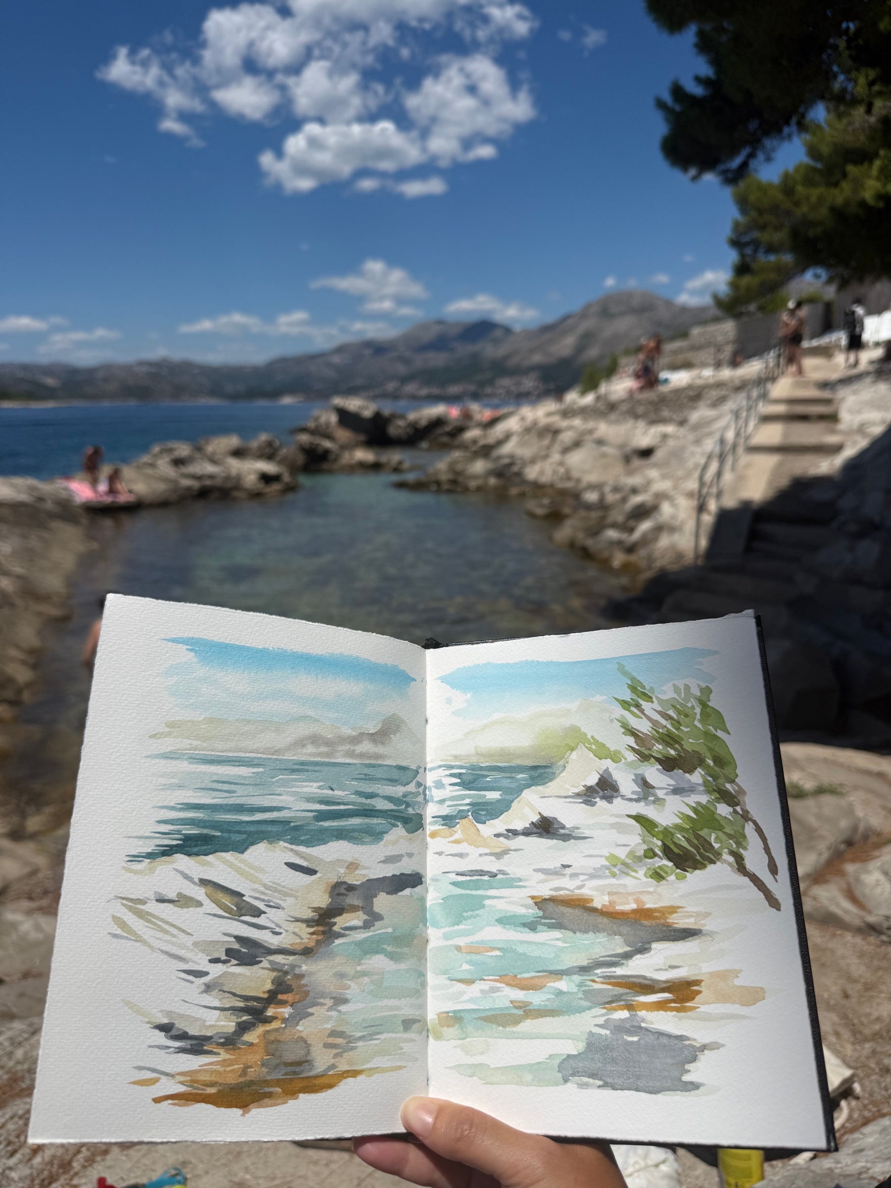 Carnet d'aquarelle représentant la mer et les rochers devant le paysage observé