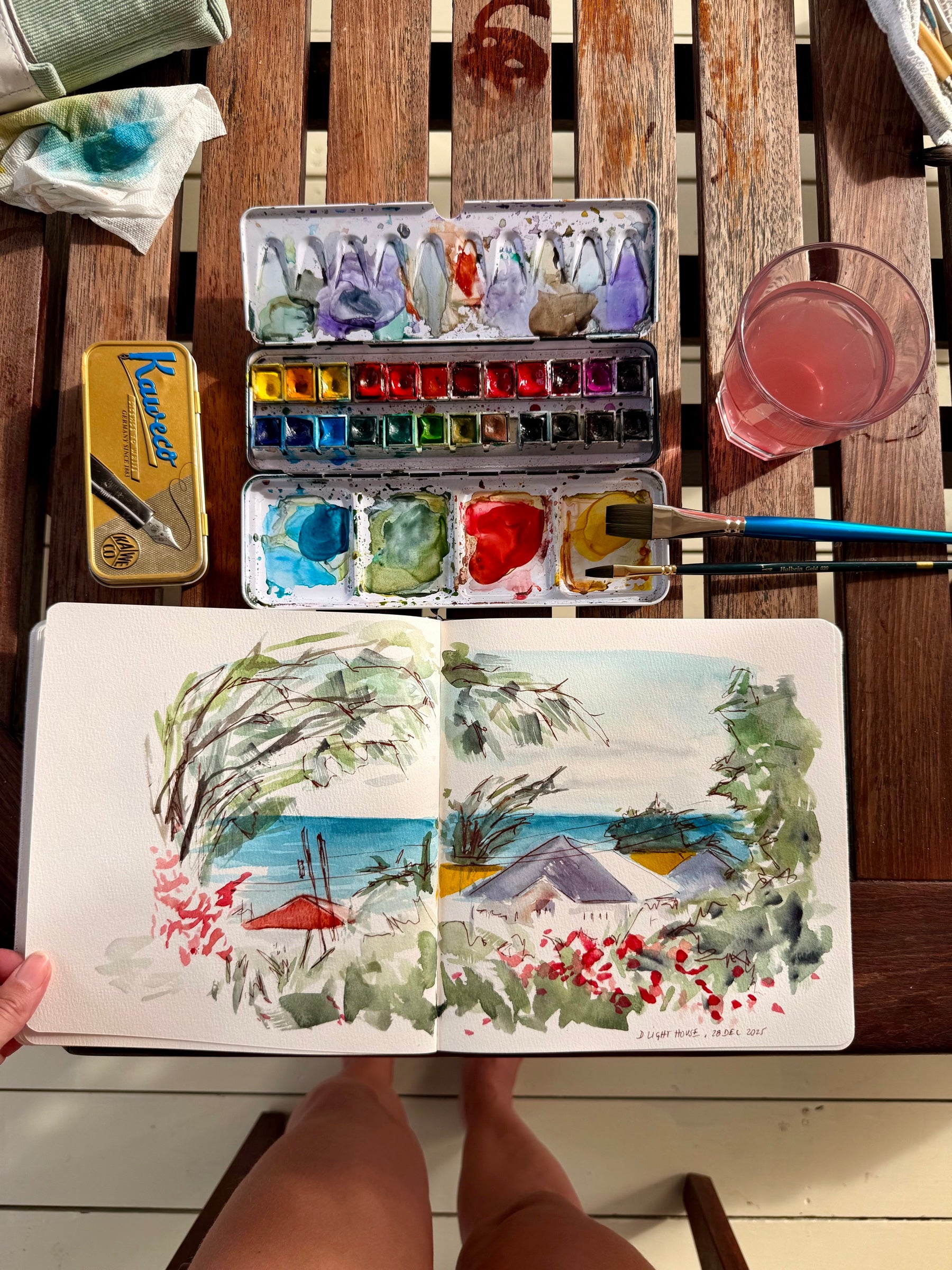 Carnet d'aquarelle coloré avec palette et pinceaux sur une table en bois