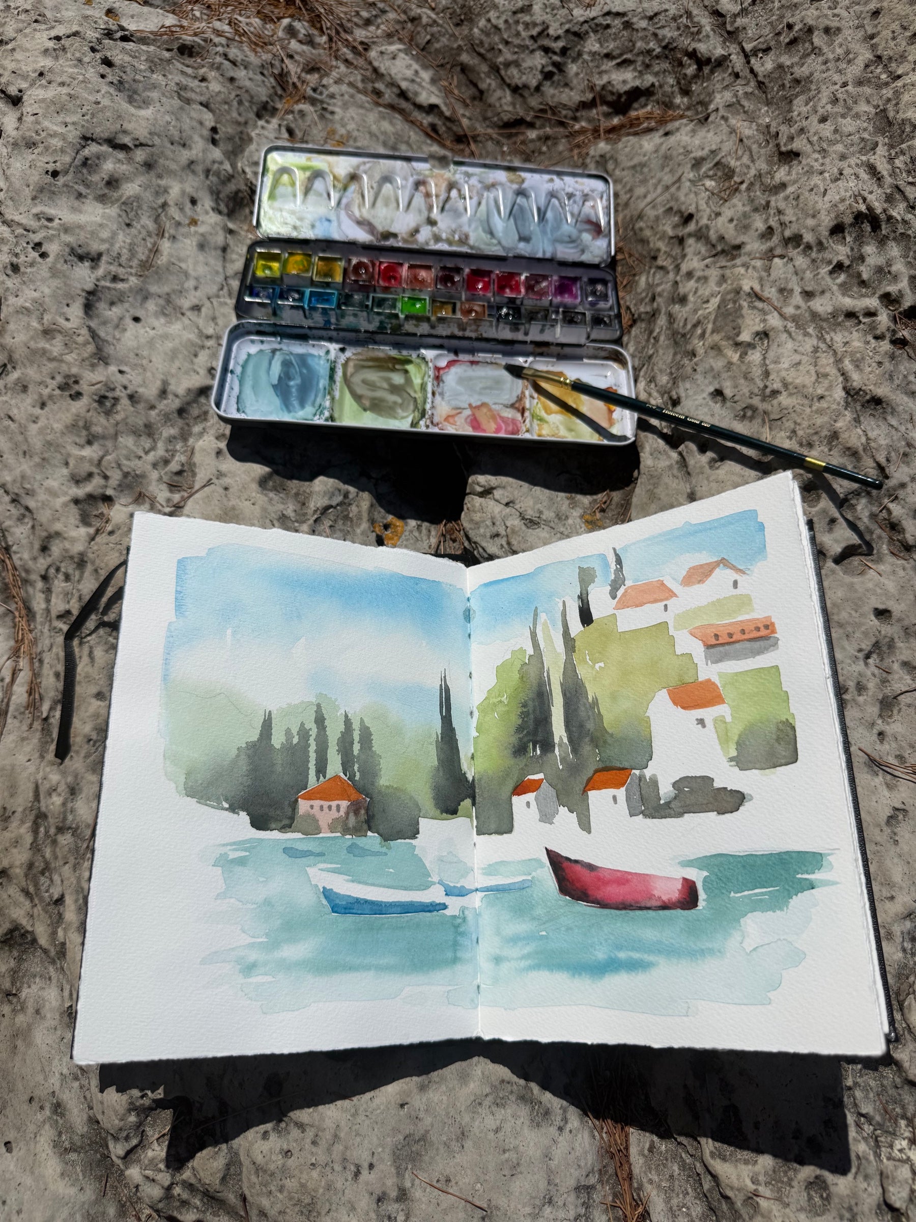 Aquarelle d'un village méditerranéen au bord de l'eau dans un carnet