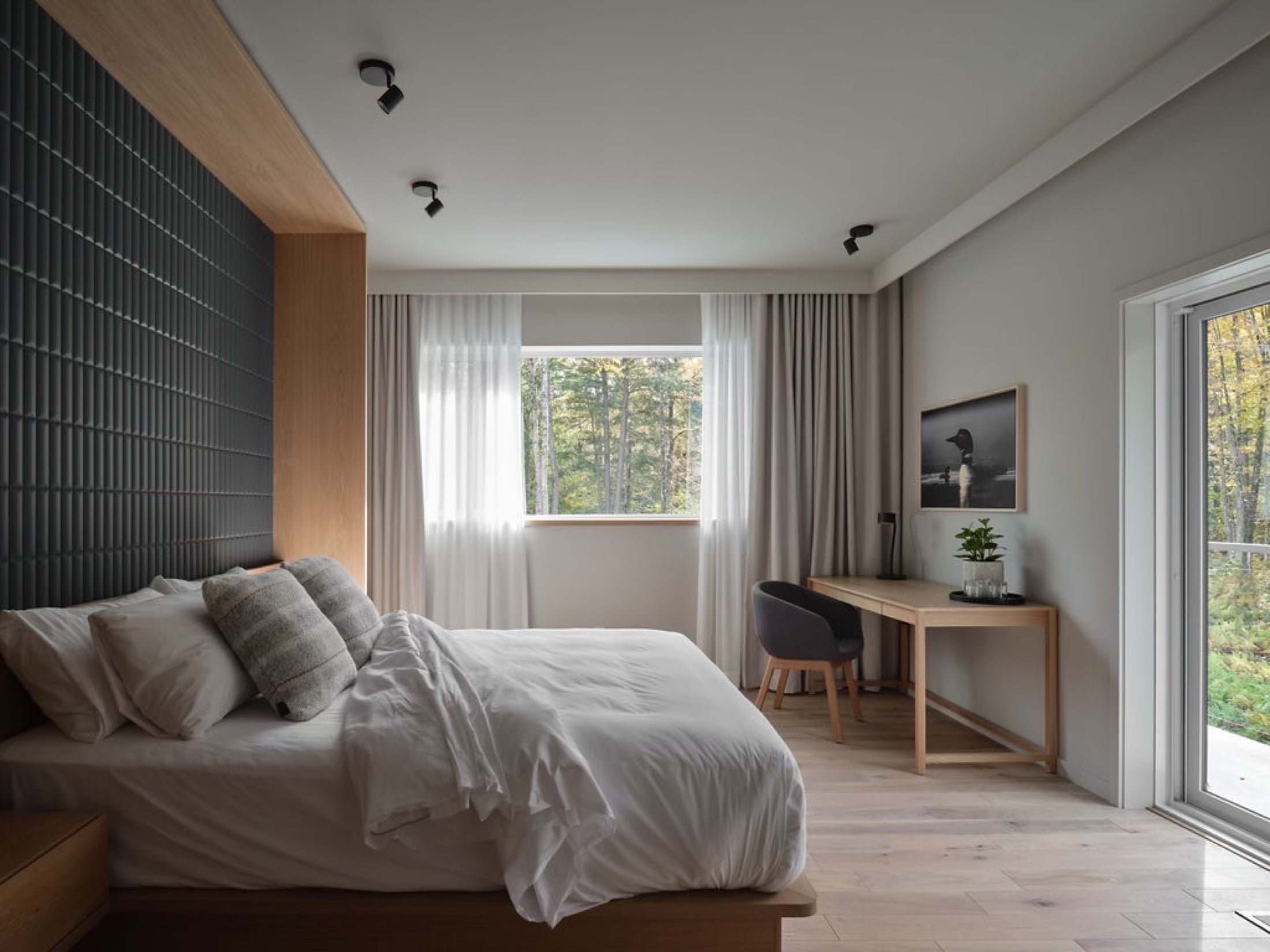 Chambre privée lumineuse du Pavillon Oasis avec lit, bureau et vue sur la forêt