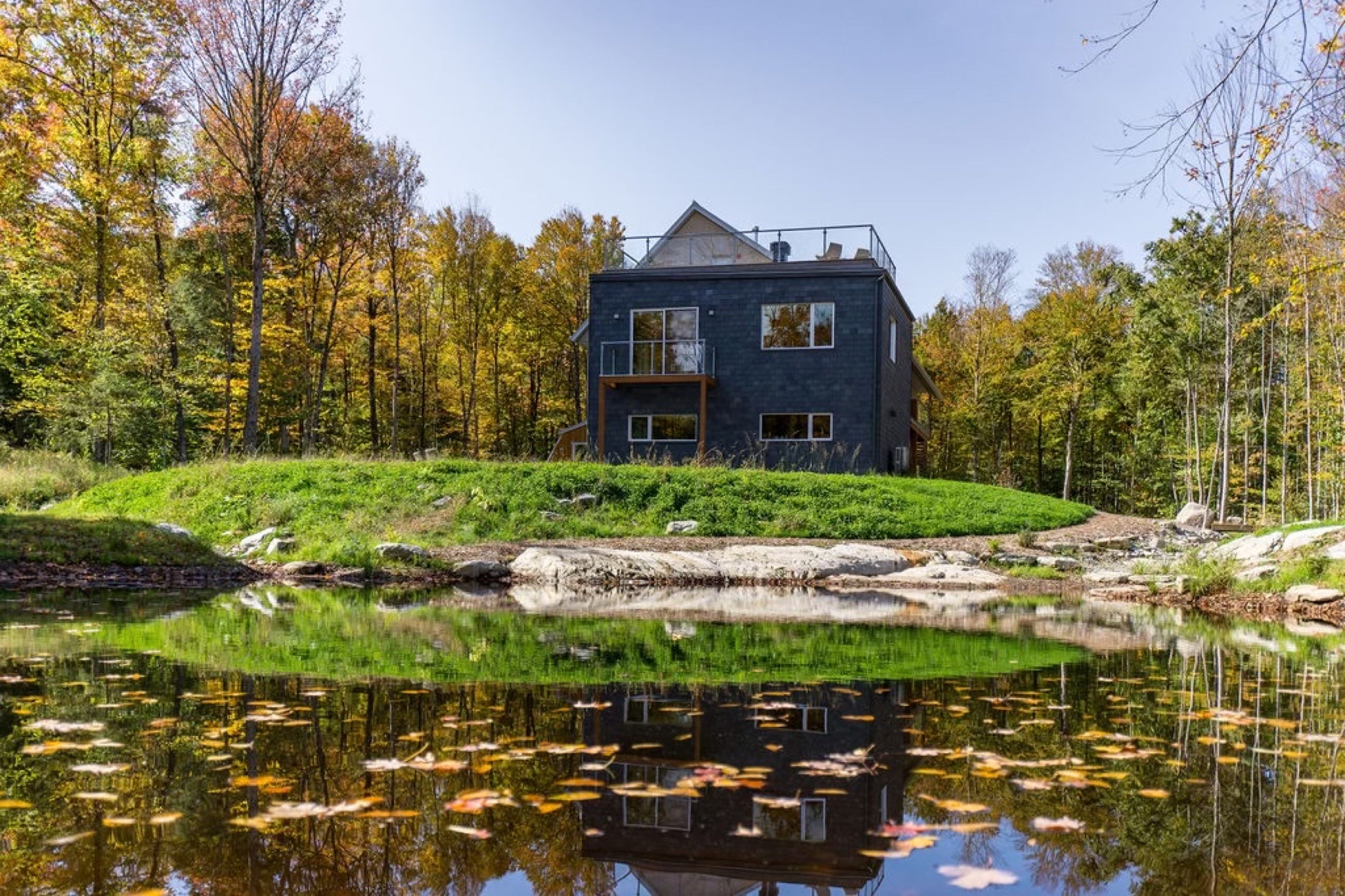 Étang calme au pied du Pavillon Oasis dans les couleurs d'automne